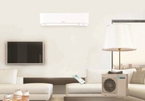 Contemporary living room featuring a beige sectional sofa, wall-mounted TV, split air conditioning units, table lamp, and air purifier in a minimalist interior