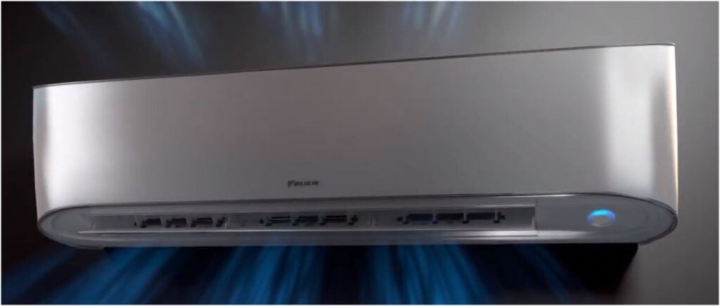 White and silver Daikin ductless air conditioning wall unit with control panel and blue indicator light.