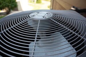 Top view of a residential air conditioning unit showing concentric circular metal fins and vents.